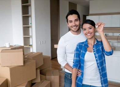 Happy couple celebrating new home with keys and moving boxes.