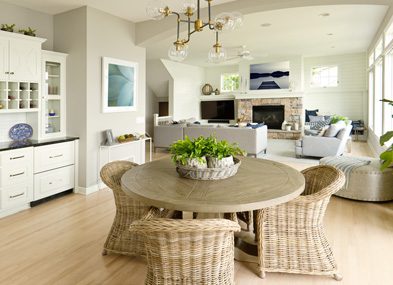 Cozy dining area with wicker chairs and a round wooden table under a modern chandelier.